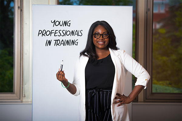 Ja’Lia Taylor standing in front of a white board that has Young Professionals in Training written on it.