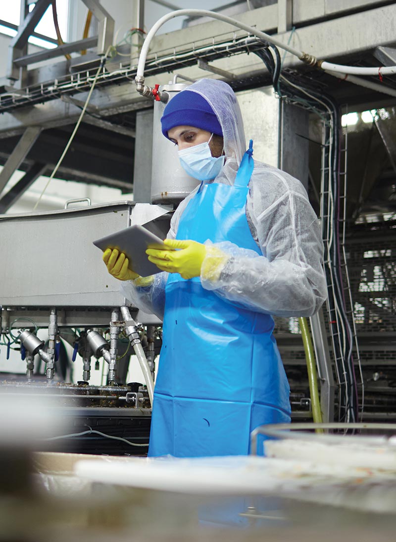 A worker in a mask looks at a tablet.