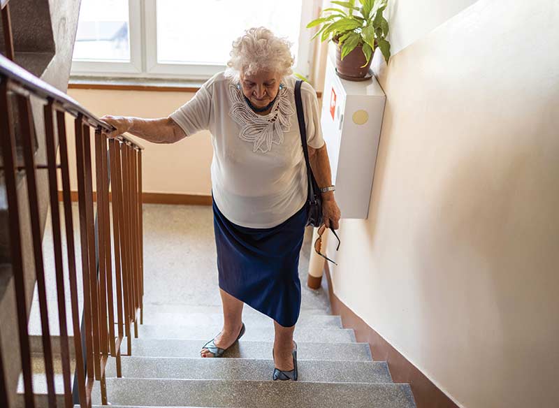An elderly woman walks up stairs