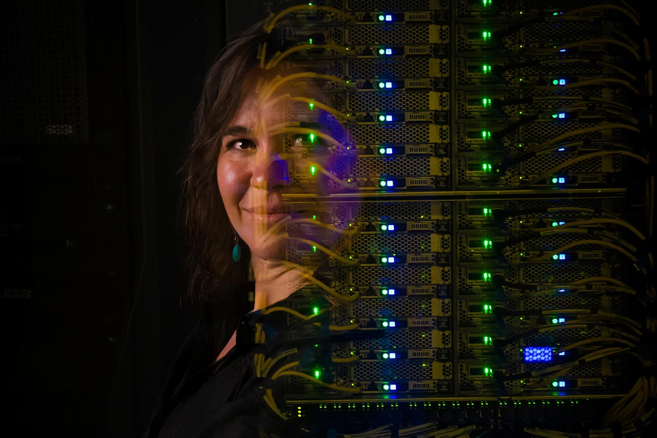 A woman stands next to a computer server tower