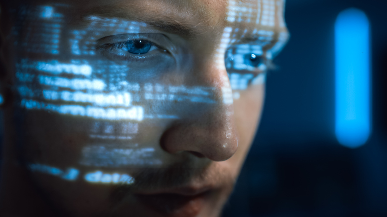  a hacker’s face showing the reflection of a computer screen