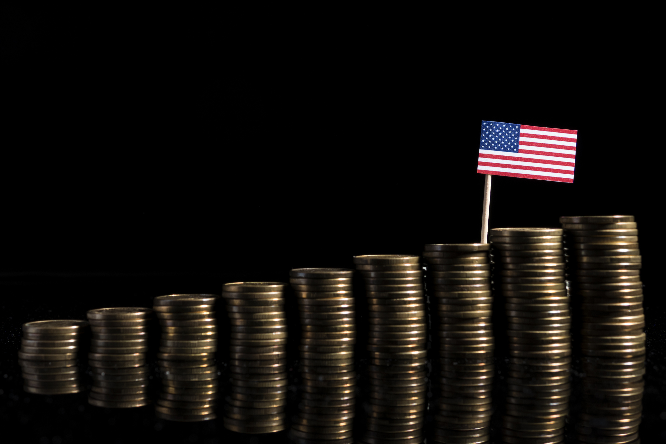 Stacks of coins and a U.S. flag.