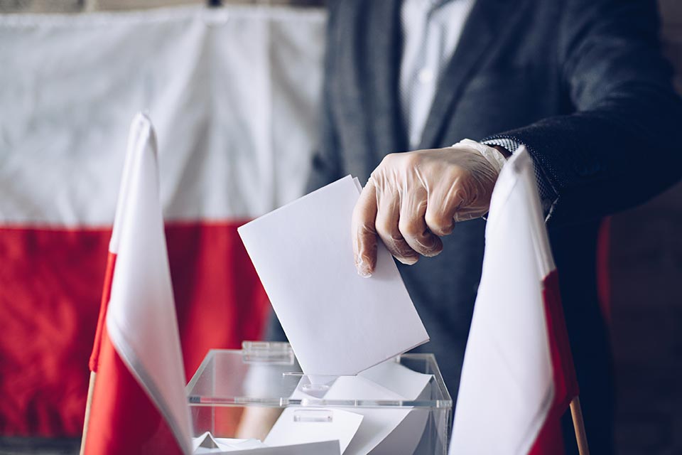 A hand drops a ballot in a box