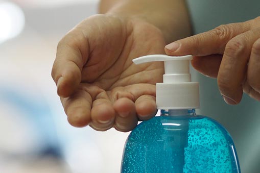 A hand dispenses antibacterial soap from a bottle