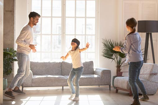 A kid and parents play in a living room