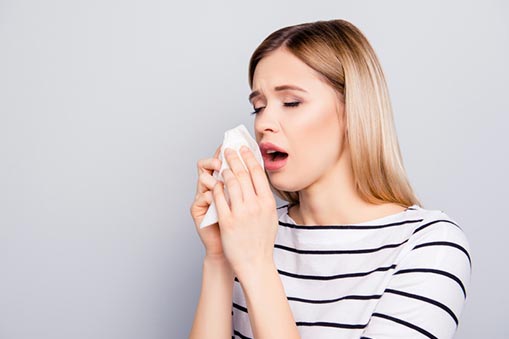 A woman coughs into a tissue