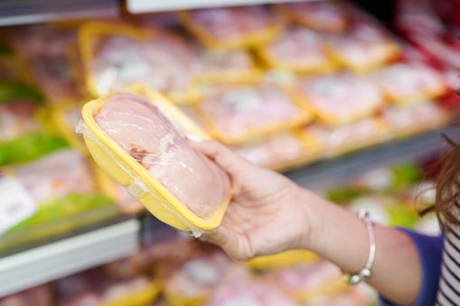 Hands holding poultry meat package at a grocery story