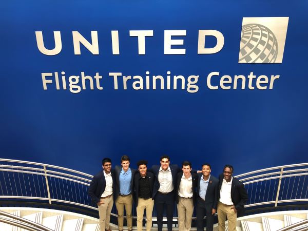 Seven Auburn students stand in front of a United Airlines sign.