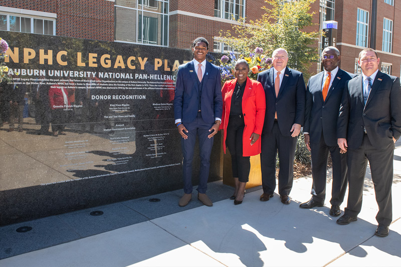 A group of people stand by Auburn's NPHC Legacy Plaza.
