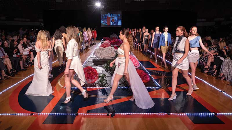 Several models walk a runway at a fashion show
