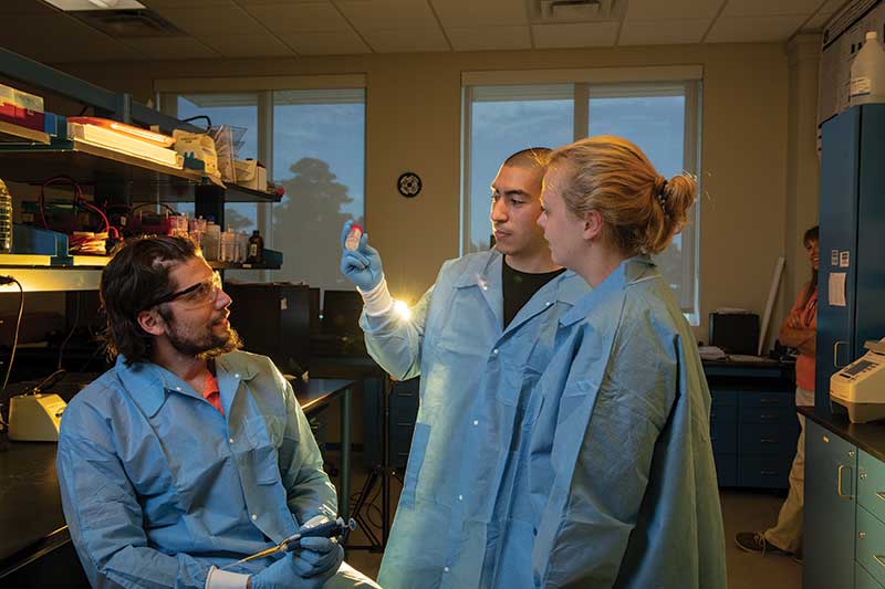 Three researchers talking in a lab