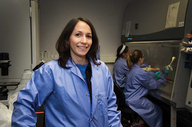 A woman stands in a lab smiling