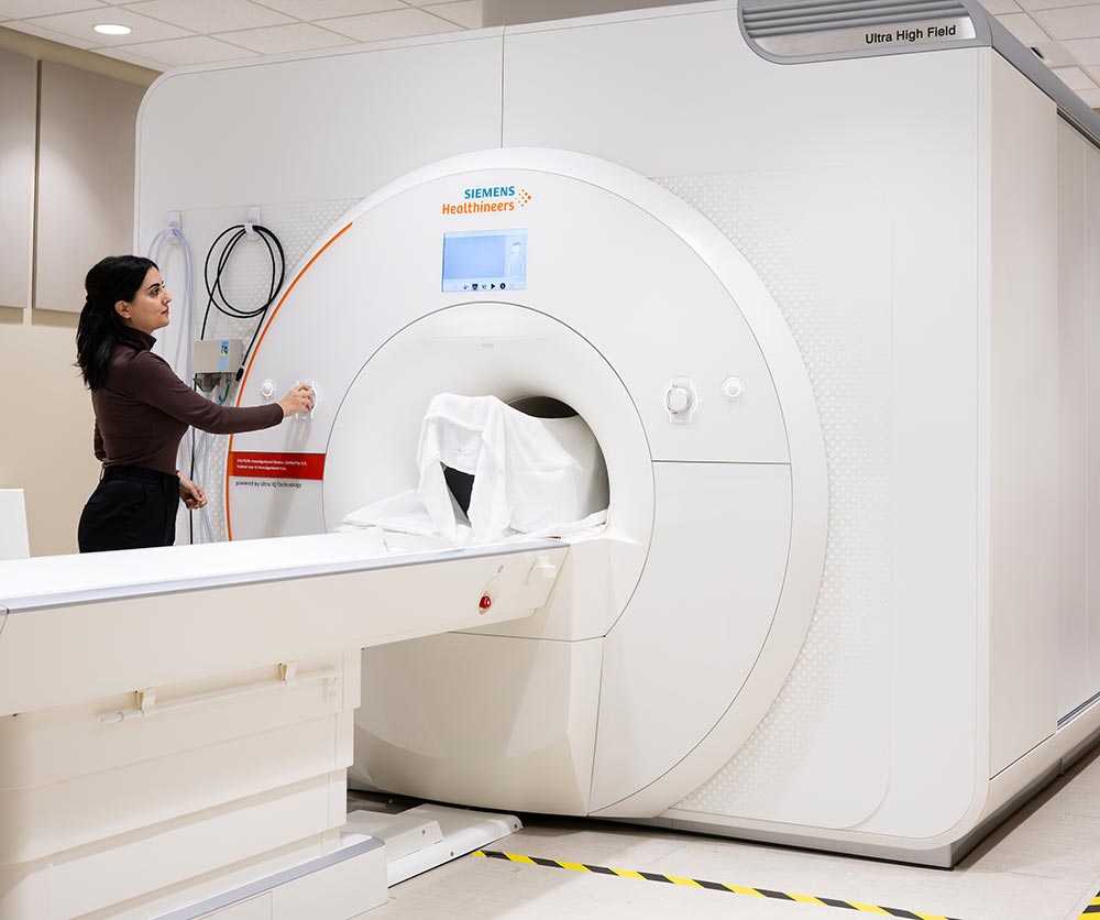 Seyedeh Nasim Adnani stands next to an MRI machine